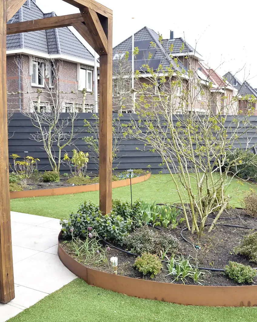 Ná: gazon met ronde cortenstalen border en een staander van de pergola